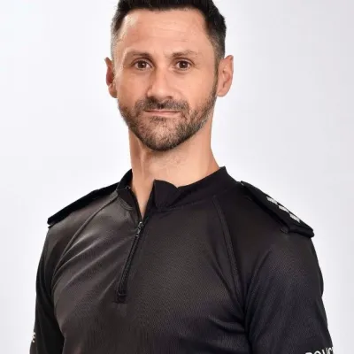 Photograph of a white man in police uniform smiling