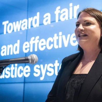 Photograph of Vicki Mulligan at an event with our branded background saying 'Toward a fair and effective justice system'