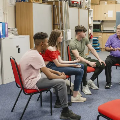 Young people sat on chairs in a circle in some kind of support or youth group setting