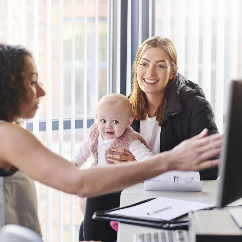 Young woman talking to professional with baby