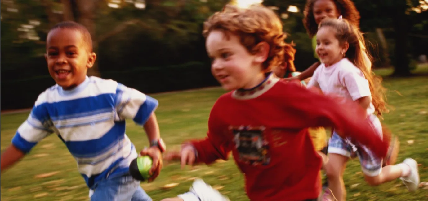 Photograph of children running outside looking happy