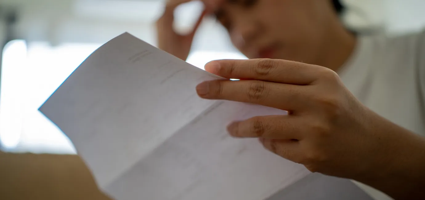 Photograph of a woman looking concerned at a letter she is holding
